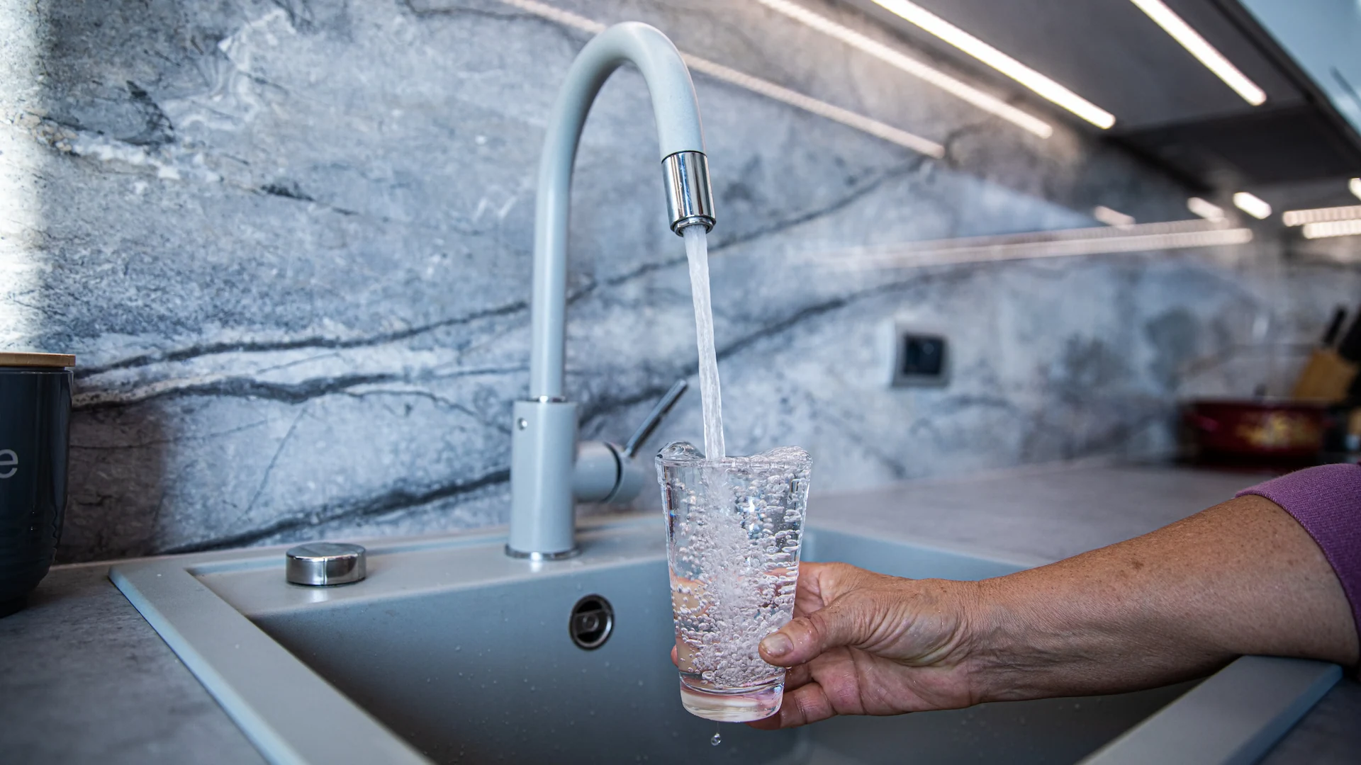 A glass being filled with water from the kitchen sink