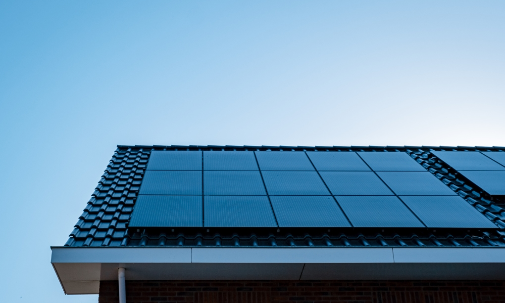 Solar panels on the top of a house and blue skies in the back