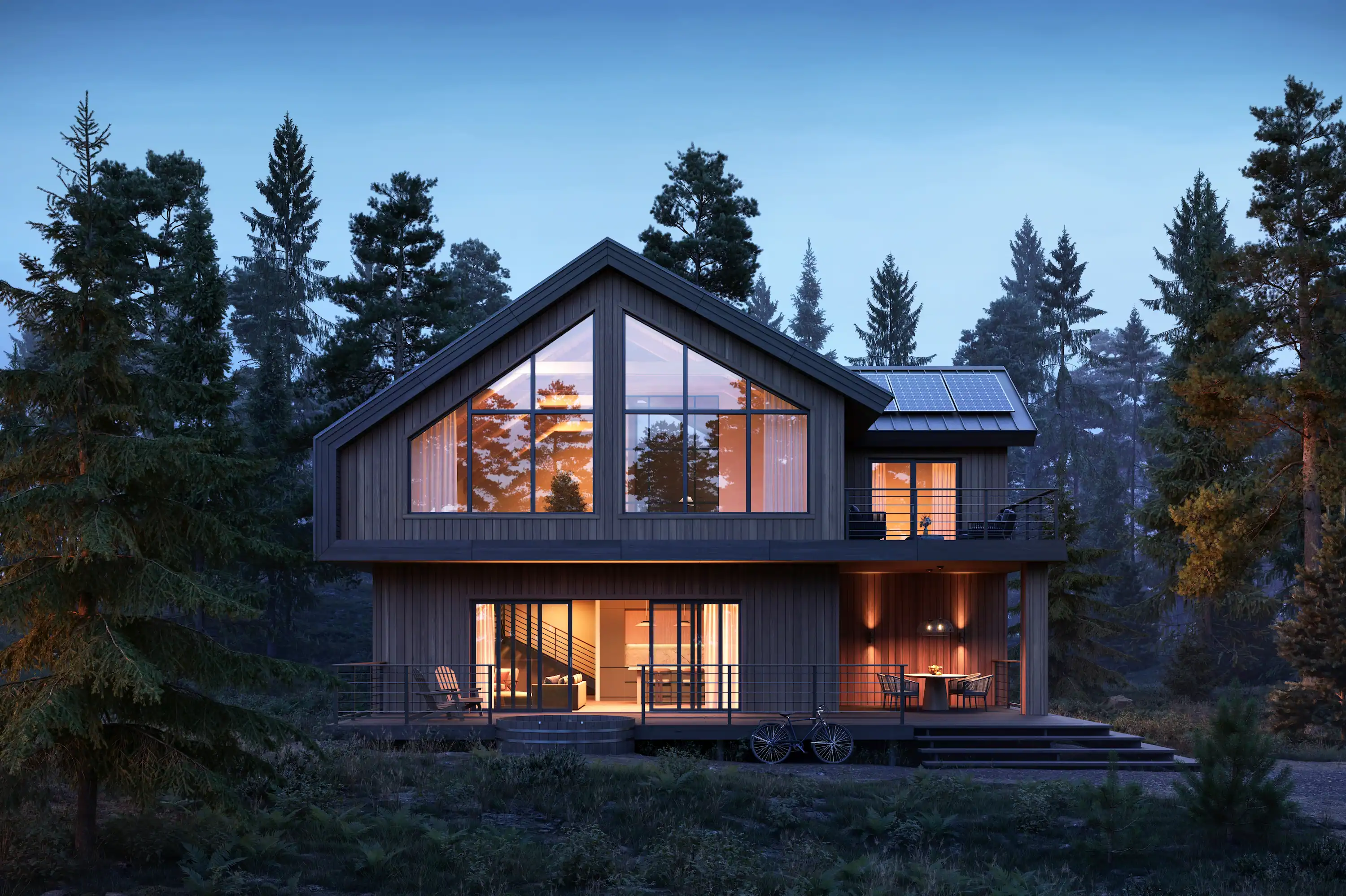 Modern cabin-style home with large windows and solar panels, illuminated at dusk and surrounded by tall pine trees
